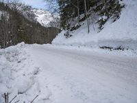 a snow - covered road in the middle of some trees and a snowy hill side