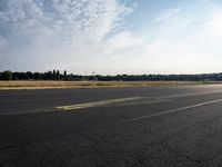 a small airplane sitting on an empty runway with trees in the background at sunset time