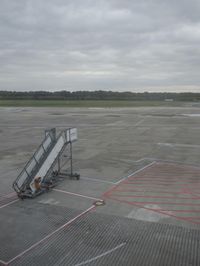 an airport tarmac has a man walking up it with a luggage cart attached to it