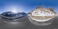 a 360 - shot picture of a snowy highway and an off road mountain side landscape