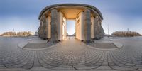 a wide view of a monument with the sun in it's middle, which is surrounded by many pillars