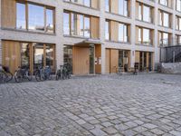 the building is made of wood and has windows on all the sides of it the bicycles are standing outside