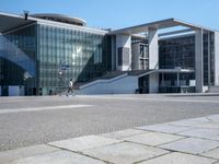 the large building has a lot of windows, and concrete bricks, around it, there is a courtyard