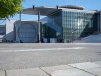 the large building has a lot of windows, and concrete bricks, around it, there is a courtyard