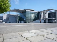 the large building has a lot of windows, and concrete bricks, around it, there is a courtyard