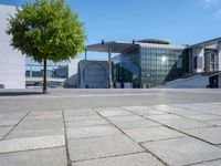 the large building has a lot of windows, and concrete bricks, around it, there is a courtyard