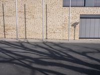 two young children walking down the street past a brick building and wall with shadow from their hands