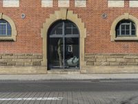 a building with windows next to a brick street corner and parking sign for the public space