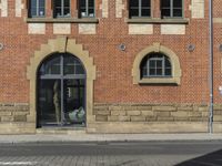 a building with windows next to a brick street corner and parking sign for the public space