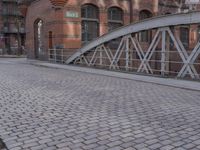 there is a brick floor with a bridge on the sidewalk in front of the building