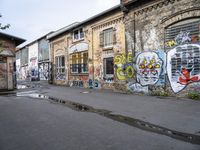 the road that leads to the two buildings is covered by street art and some colorful graffiti