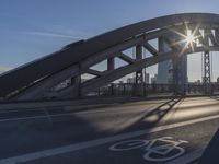 the sun shines brightly from behind the bridge as the cyclist rides on it through the city