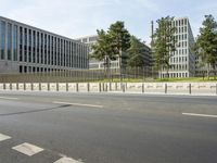 a view of the street and street corner near an office building with tall trees and fences