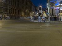 a city street with lots of people walking, sitting and on bikes at night time