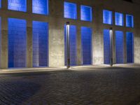 a building with some very tall windows and light in them at night time lite up with blue lights