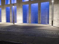 a building with some very tall windows and light in them at night time lite up with blue lights