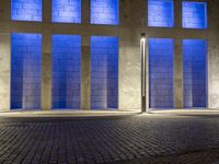 a building with some very tall windows and light in them at night time lite up with blue lights