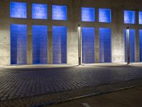 a building with some very tall windows and light in them at night time lite up with blue lights