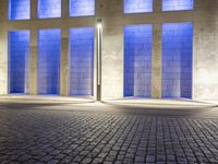 a building with some very tall windows and light in them at night time lite up with blue lights