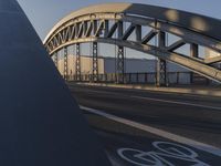 a bicycle path bridge spanning the middle of an open road with graffiti on the wall