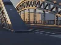 a bicycle path bridge spanning the middle of an open road with graffiti on the wall