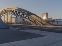 a bicycle path bridge spanning the middle of an open road with graffiti on the wall