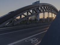 a bicycle path bridge spanning the middle of an open road with graffiti on the wall