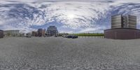 a view of a road and buildings with cloudy skies in the background while fisheye lens is done