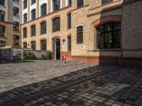 a sidewalk with chairs next to the brick building on the side, some have stairs and some buildings in the background