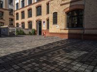 a sidewalk with chairs next to the brick building on the side, some have stairs and some buildings in the background