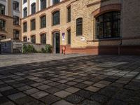 a sidewalk with chairs next to the brick building on the side, some have stairs and some buildings in the background