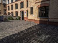 a sidewalk with chairs next to the brick building on the side, some have stairs and some buildings in the background