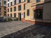 a sidewalk with chairs next to the brick building on the side, some have stairs and some buildings in the background