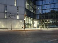 a paved street in the middle of buildings with tall windows at night, with car lights on