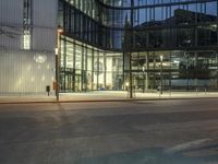 a paved street in the middle of buildings with tall windows at night, with car lights on