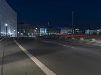 large building on the street with lights in front and other buildings nearby at night with no one moving