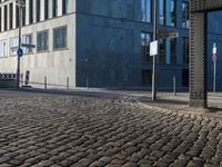 an empty parking sign next to a tall grey building on a sidewalk in a city