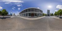 an image of a curved circular building on a road that has trees in it and grass on both sides