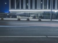 the empty city road is empty by the tall building in the background at night with light streaking on the buildings