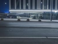 the empty city road is empty by the tall building in the background at night with light streaking on the buildings