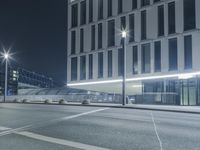 the empty city road is empty by the tall building in the background at night with light streaking on the buildings