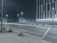 the empty city road is empty by the tall building in the background at night with light streaking on the buildings