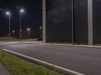 an empty road with a closed garage building in the background at night, as traffic passes by