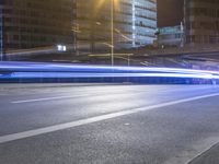 a street at night with many cars passing under the bridge and on the road there is long exposure on camera