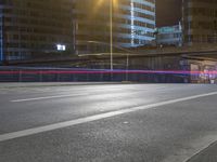 a street at night with many cars passing under the bridge and on the road there is long exposure on camera