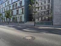 a manhole cover in the middle of a street with the reflection of a building in the glass of it