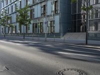 a manhole cover in the middle of a street with the reflection of a building in the glass of it