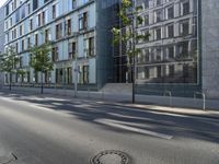 a manhole cover in the middle of a street with the reflection of a building in the glass of it