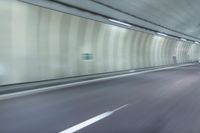 a blurry photo of a highway in an empty tunnel, with light coming through the opening