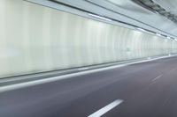 a blurry photo of a highway in an empty tunnel, with light coming through the opening